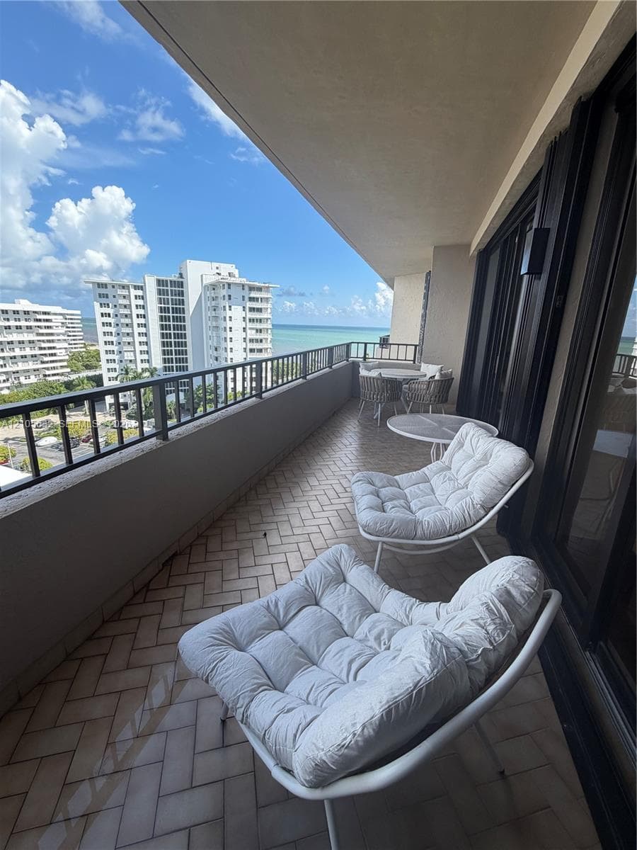 Covered balcony featuring herringbone-patterned tile flooring, metal railing, and ocean horizon