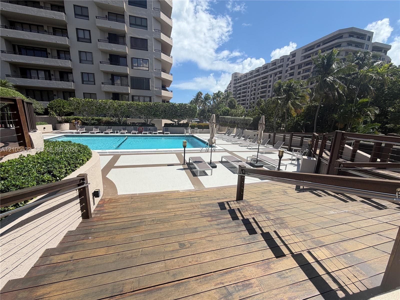 Outdoor swimming pool featuring a concrete deck and a wooden plank boardwalk with metal railings