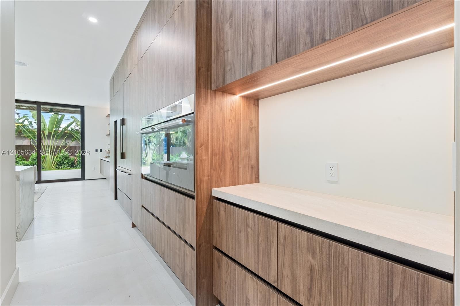 Full-height wood-finish cabinetry featuring integrated appliances, minimalist hardware, quartz countertops, and built-in under-cabinet LED lighting