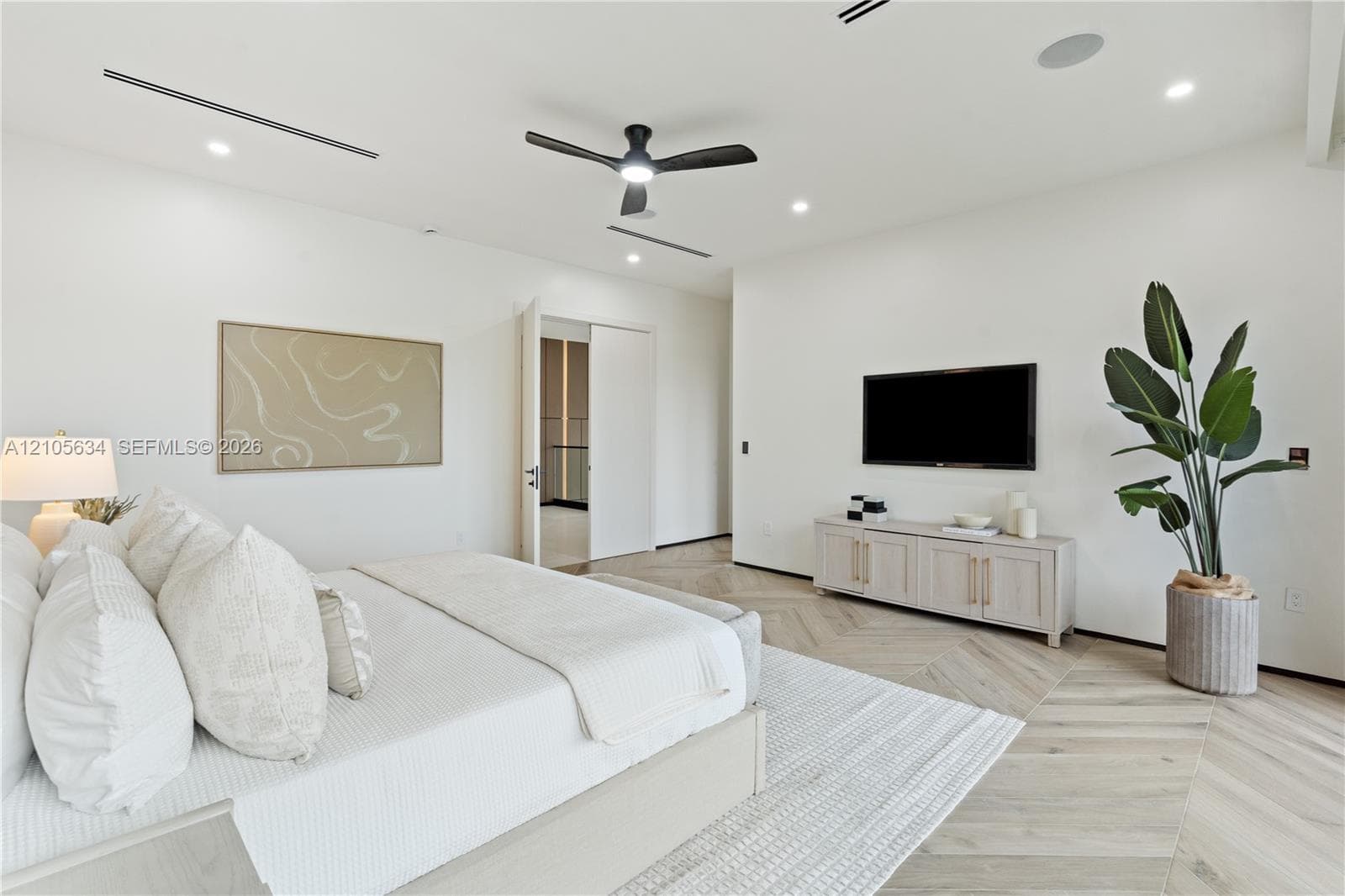 Herringbone-patterned wood-finish flooring, recessed linear lighting, and integrated ceiling speakers