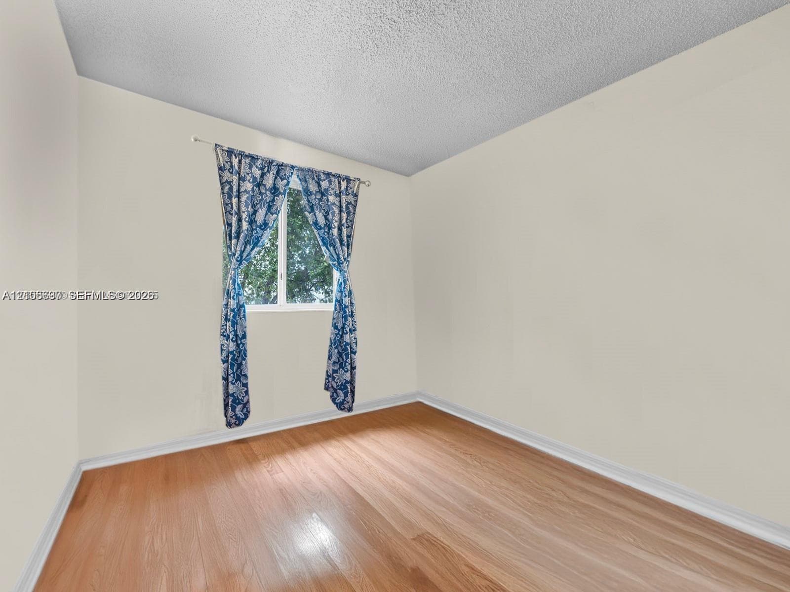 Neutral-toned interior space featuring wood-finish flooring and a single-pane window