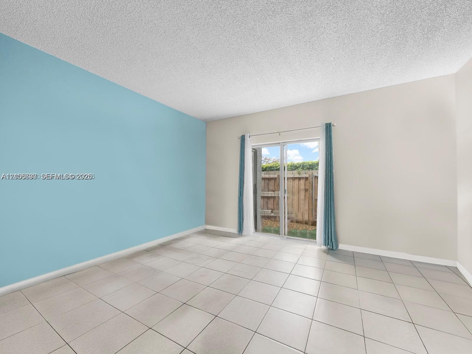 Interior space featuring large-format ceramic tile flooring, a textured ceiling, and a sliding glass door providing exterior access
