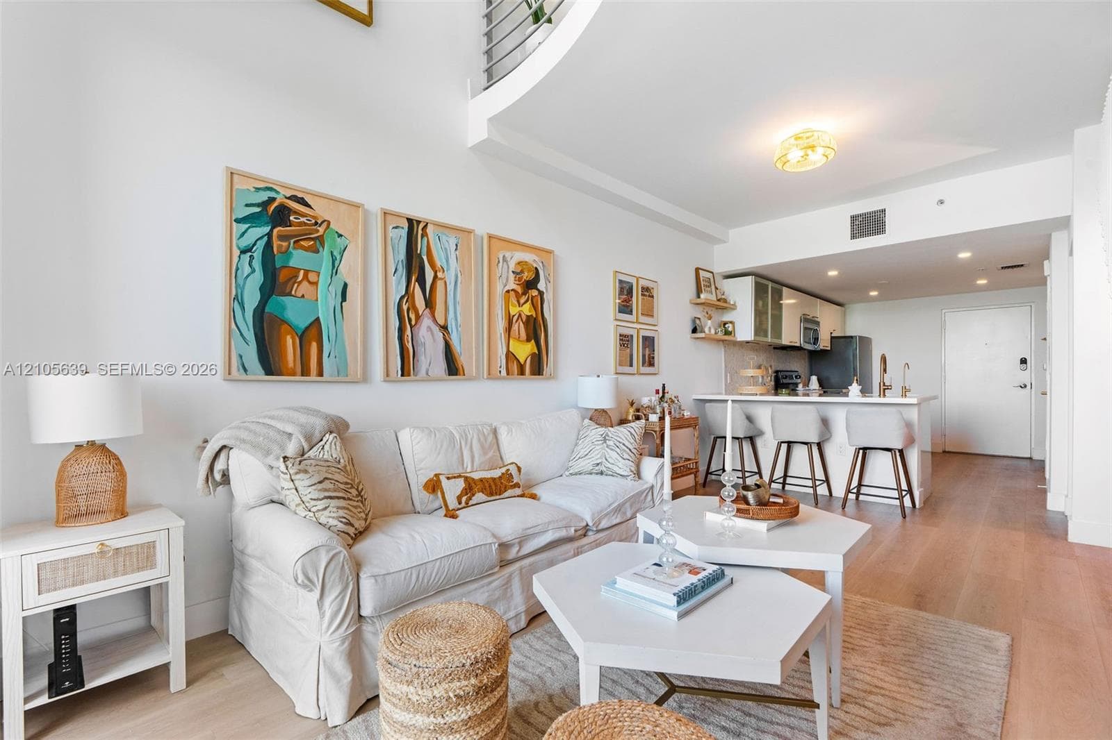 Double-height ceiling, wood-finish flooring, kitchen island with breakfast bar seating, and minimalist cabinetry