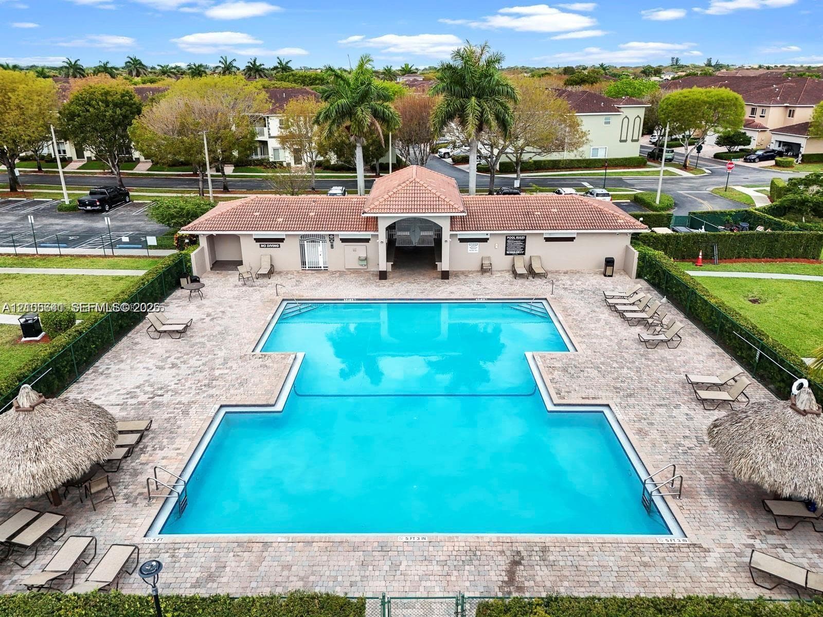 Swimming pool with paver decking, covered pavilion, tile roofing, and integrated tiki-style structures