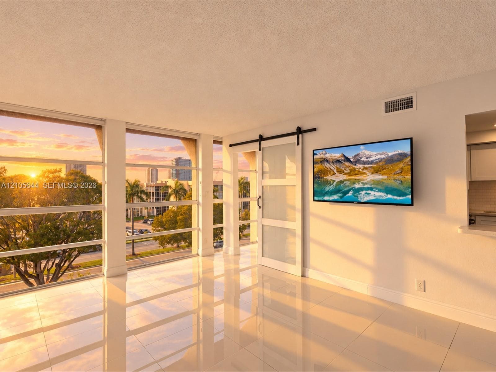 Expansive floor-to-ceiling windows, polished tile flooring, frosted-glass barn-style sliding door with matte black hardware, and an urban backdrop