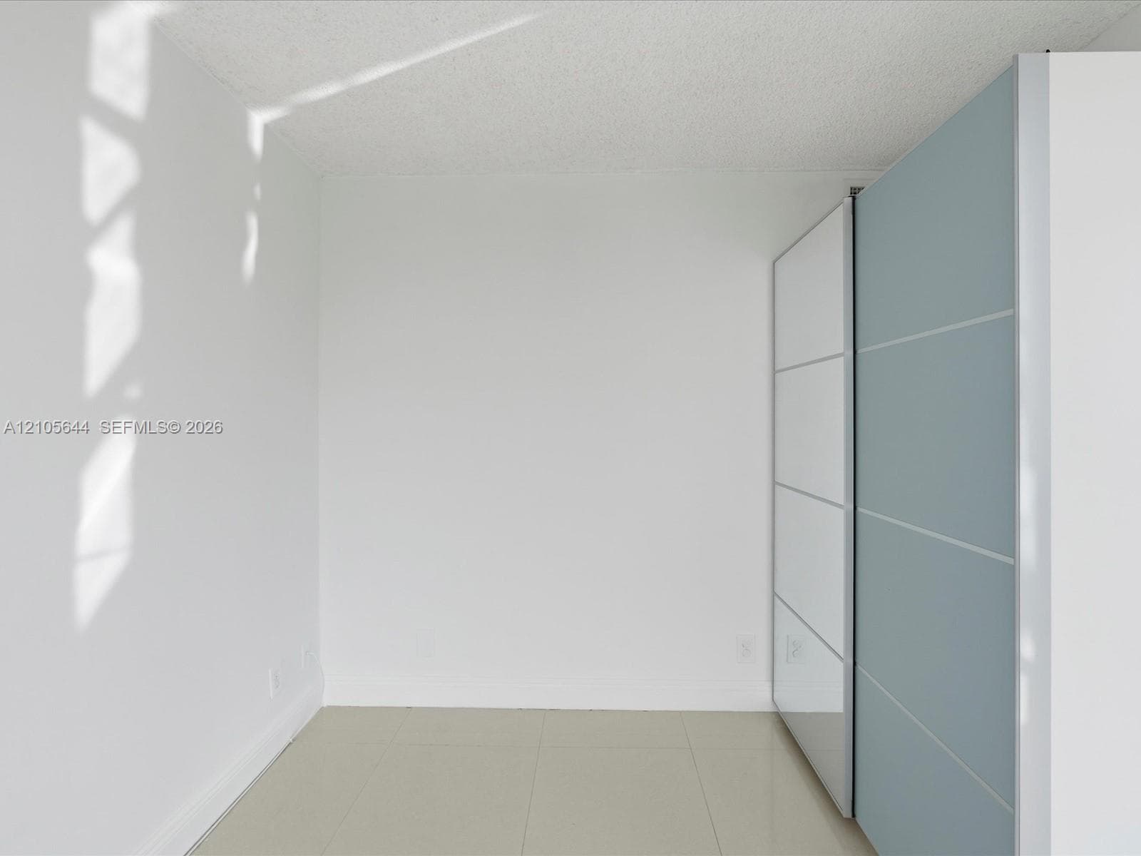 Built-in floor-to-ceiling cabinetry featuring high-gloss white and blue-grey paneling with metallic hardware, paired with neutral large-format tile flooring