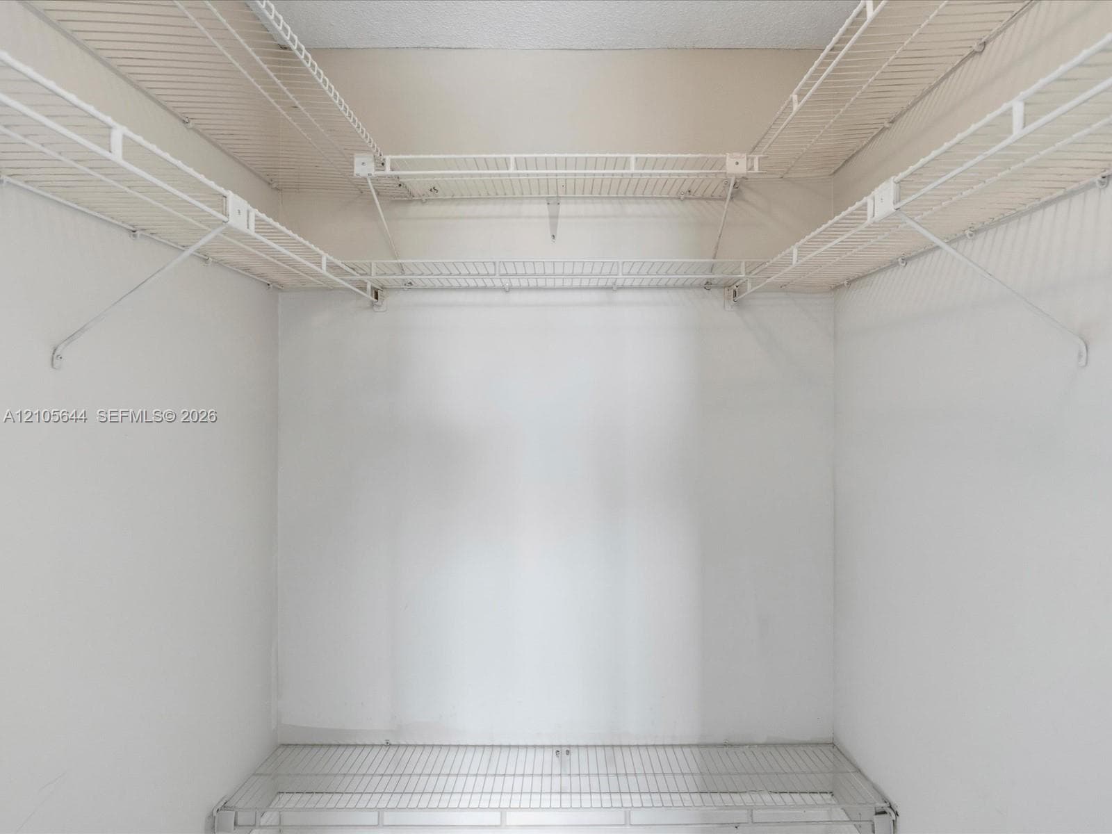 Storage space featuring white wire shelving units across three walls and a lower wire shelf