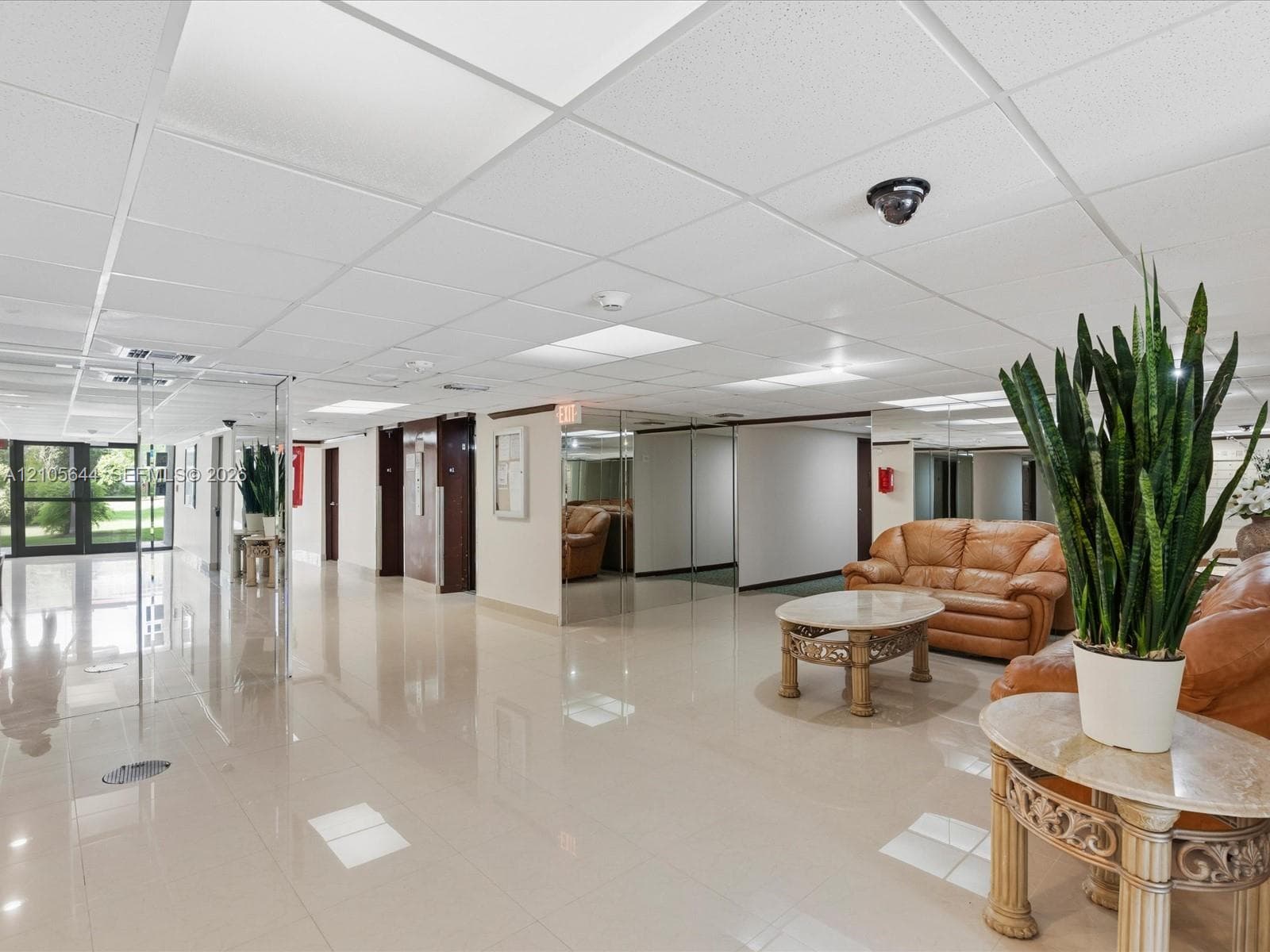 Polished tile flooring, suspended drop ceiling with recessed lighting, mirrored wall accents, and glass entry doors