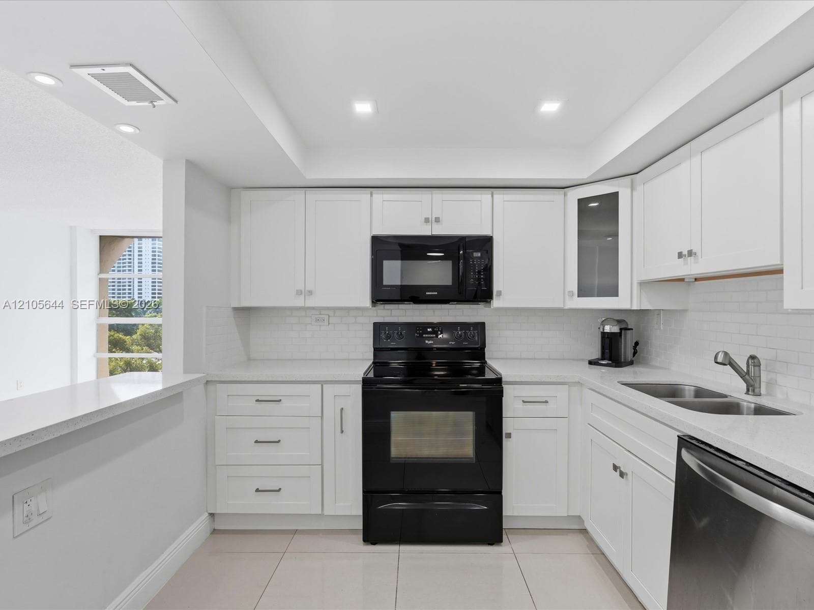Kitchen featuring white shaker cabinetry, quartz countertops, subway tile backsplash, recessed ceiling lighting, and black appliances