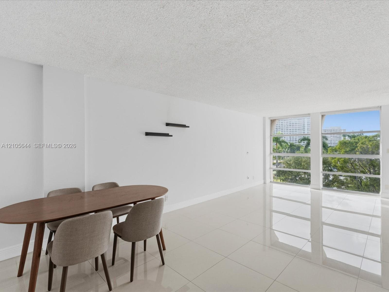Open-concept living space featuring high-gloss tile flooring, floor-to-ceiling windows, and built-in wall shelving