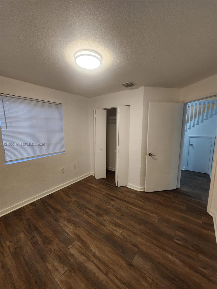 Wood-finish flooring, interior closet with bi-fold doors, and ceiling-mounted flush light fixture