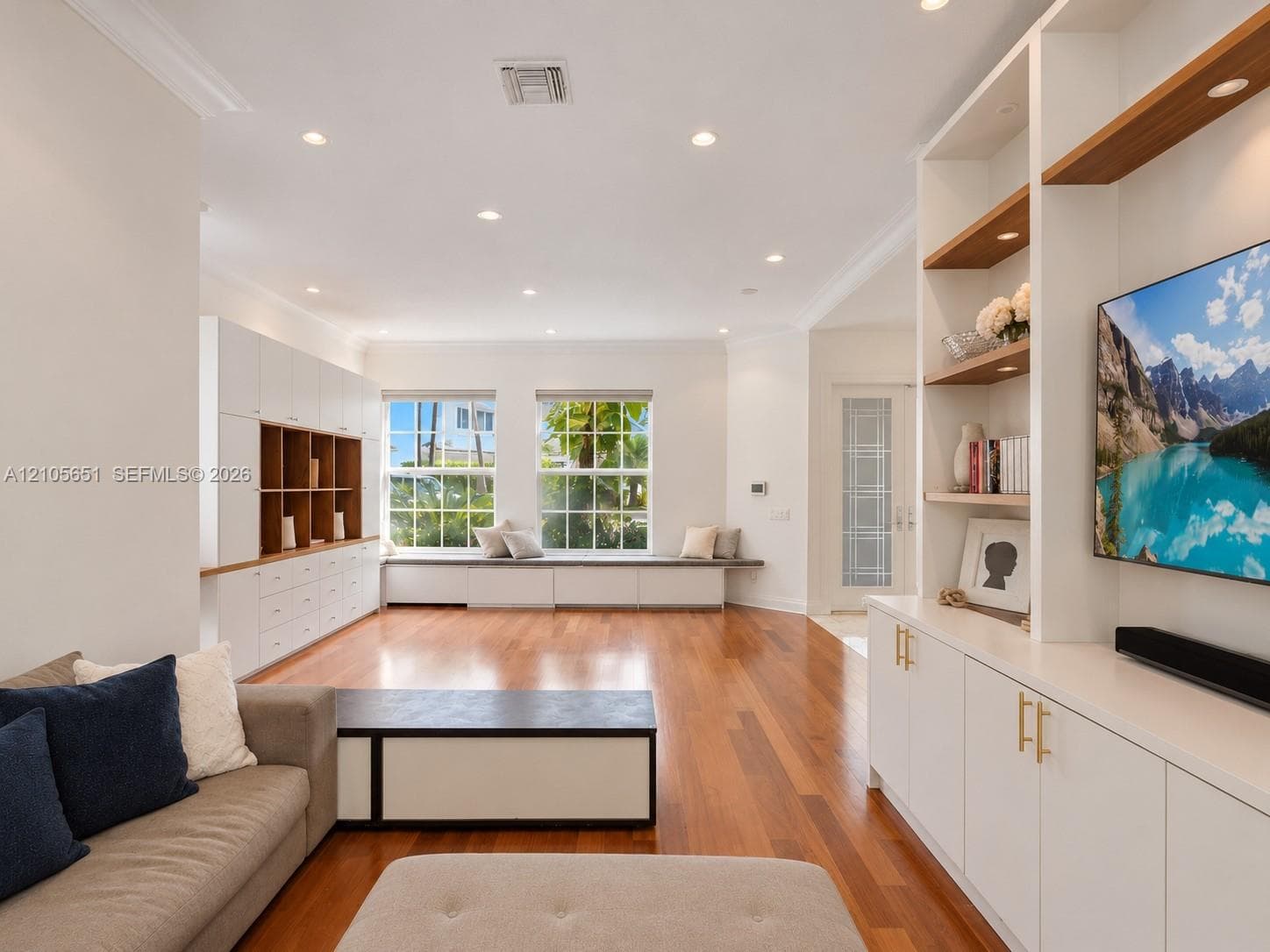 Living space featuring wood-finish flooring, recessed lighting, expansive built-in cabinetry, custom shelving, and a window seat