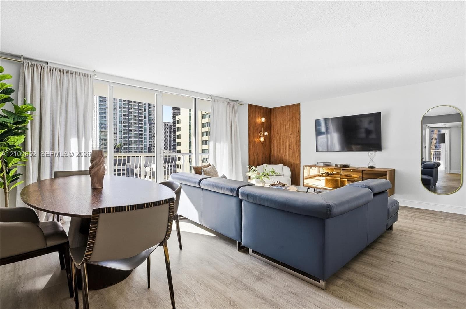 Living space featuring floor-to-ceiling windows, wood-finish flooring, and an accent wall with wood-panel detailing