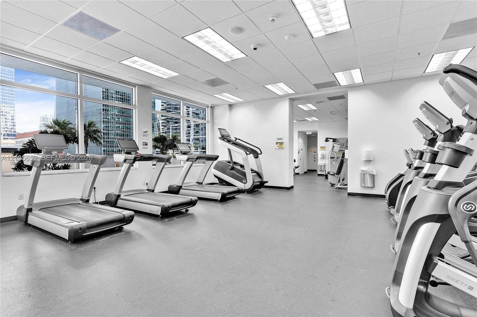 Fitness center featuring expansive floor-to-ceiling windows, recessed drop-ceiling lighting, and rubberized flooring