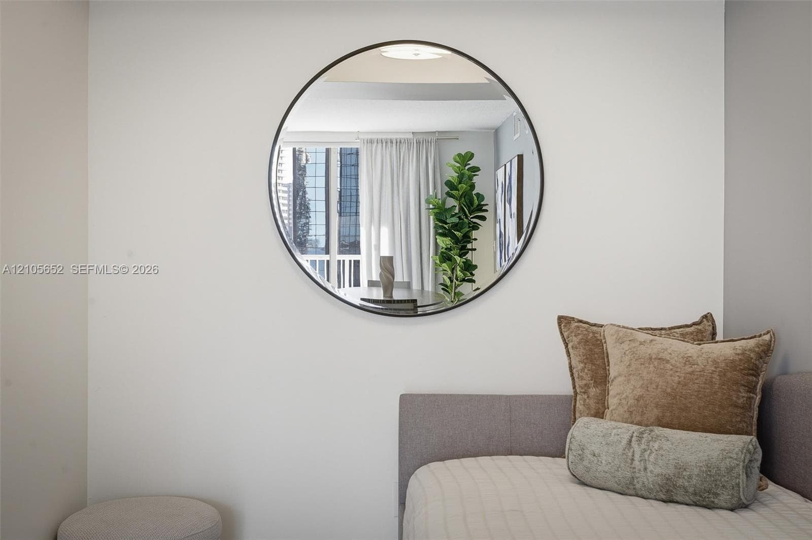 Circular wall-mounted mirror with a thin matte black frame