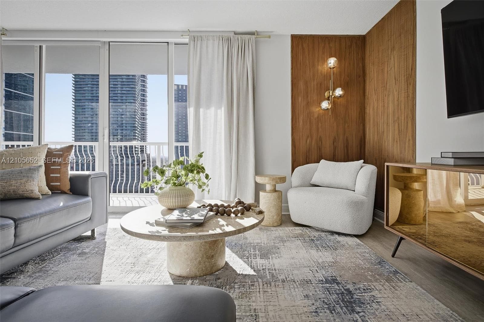 Living area featuring floor-to-ceiling windows, wood-finish wall paneling, and an integrated multi-globe wall sconce