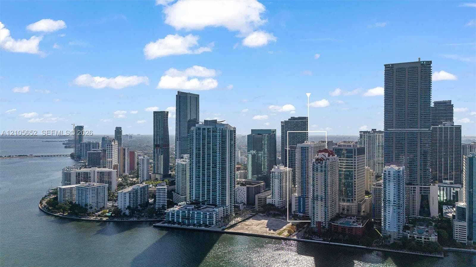 High-rise building featuring a glass facade, multiple balconies, and a distinctive multi-tiered roofline, situated within a coastal urban landscape