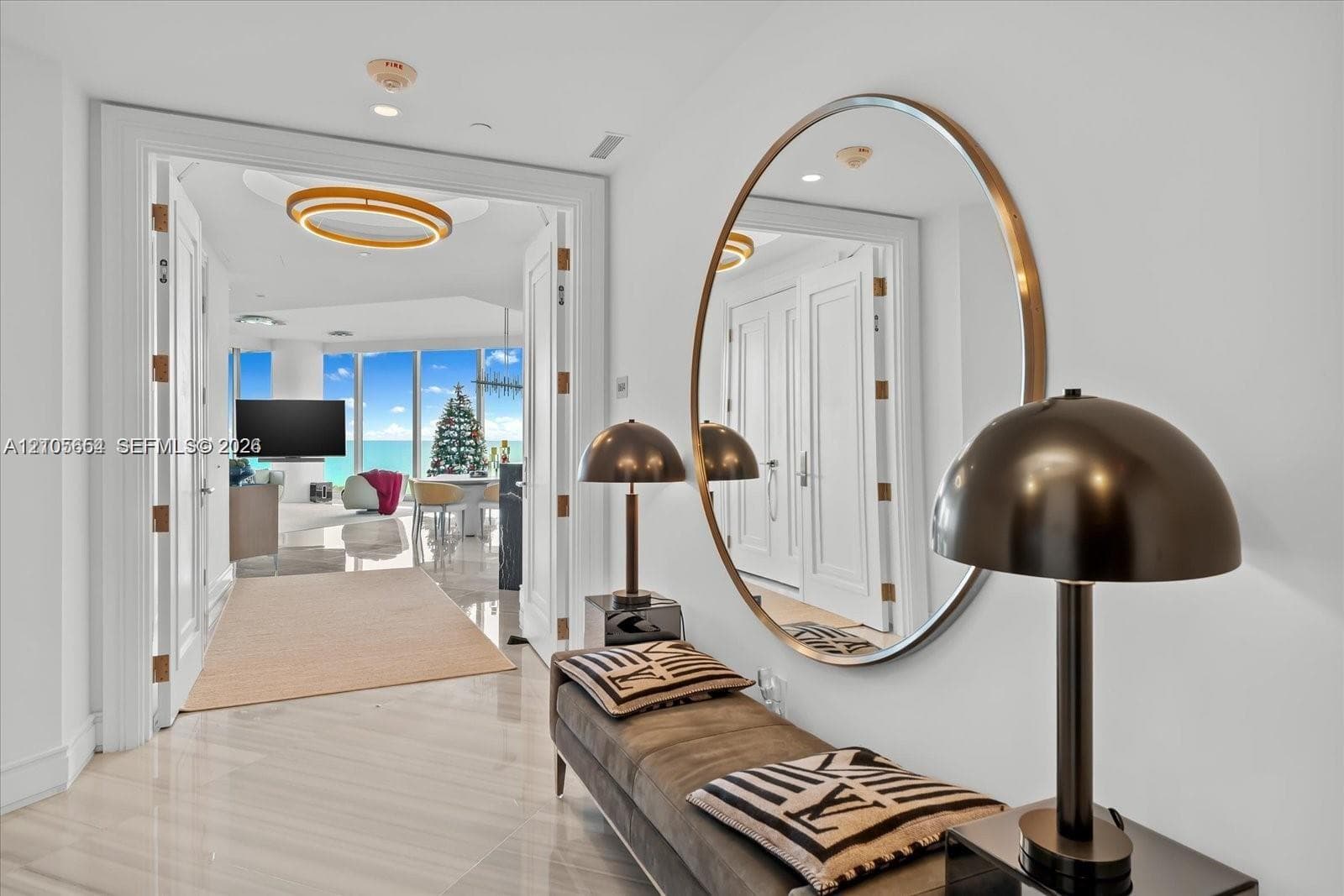 Entryway featuring polished stone flooring, custom millwork door casings, and a large circular wall-mounted mirror