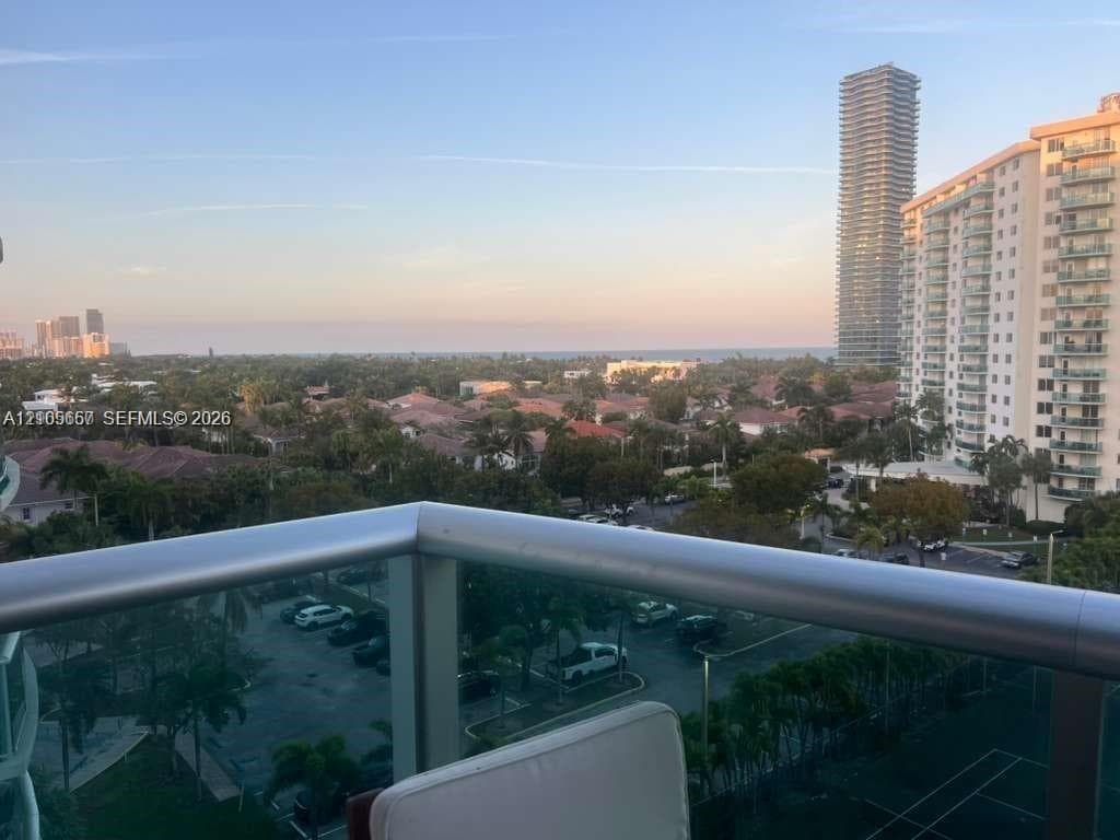 Balcony featuring a metal railing with glass panels and an expansive skyline and coastal horizon