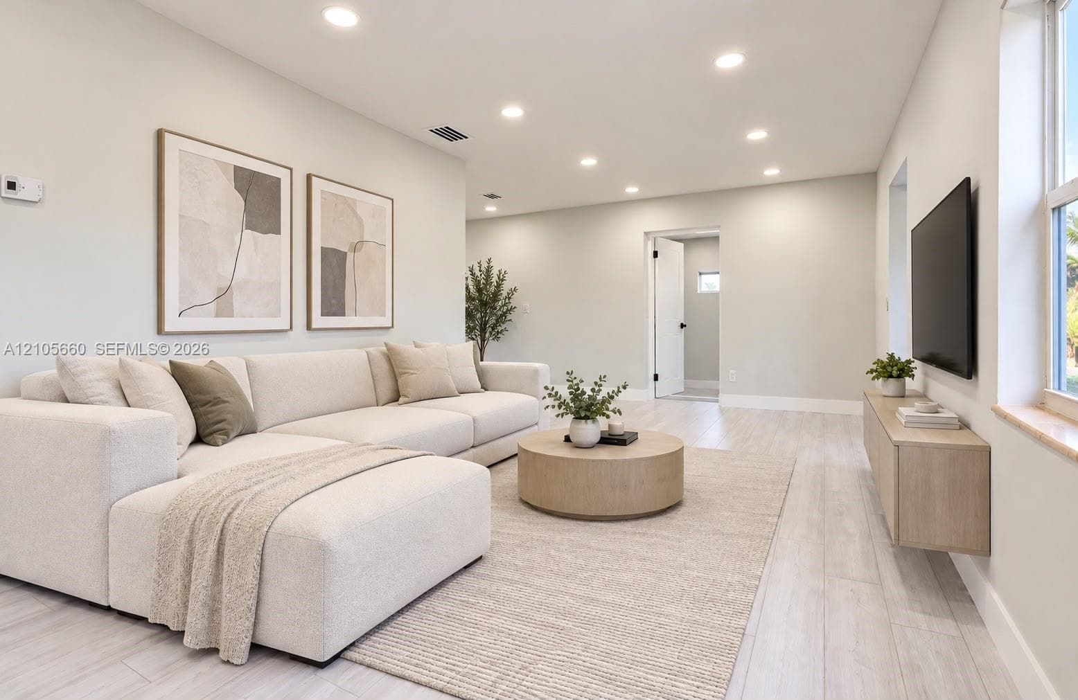 Neutral-toned interior featuring wood-finish flooring, recessed lighting, and a wall-mounted floating media console