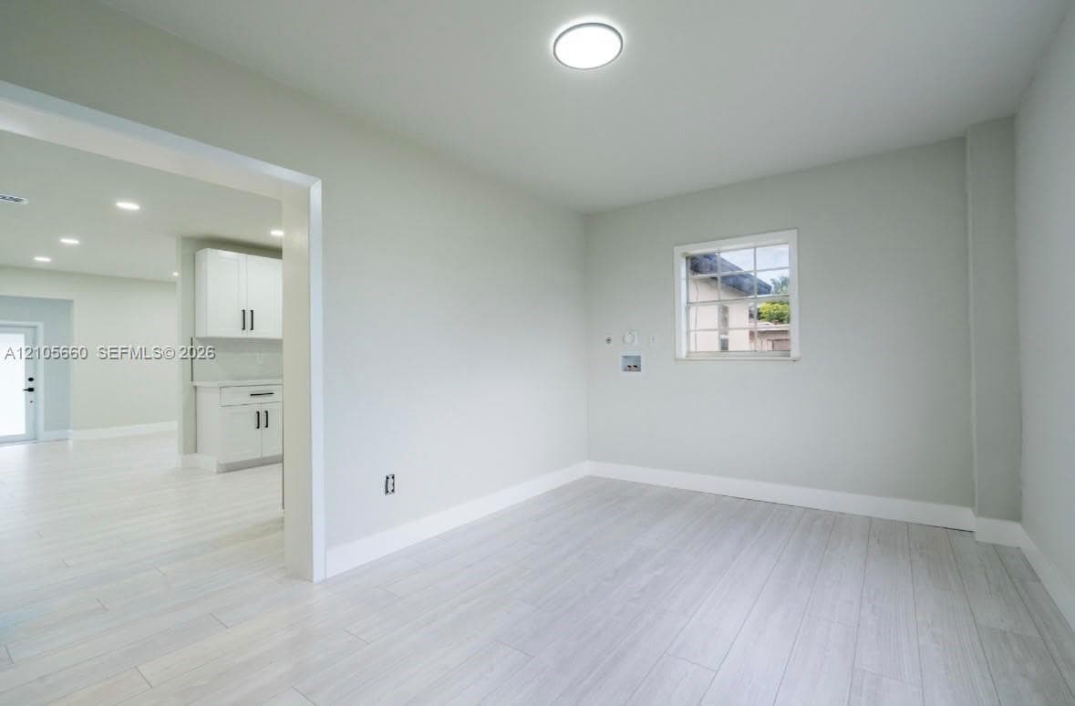 Light-toned wood-finish flooring, recessed ceiling lighting, and a single-pane window with a grid pattern