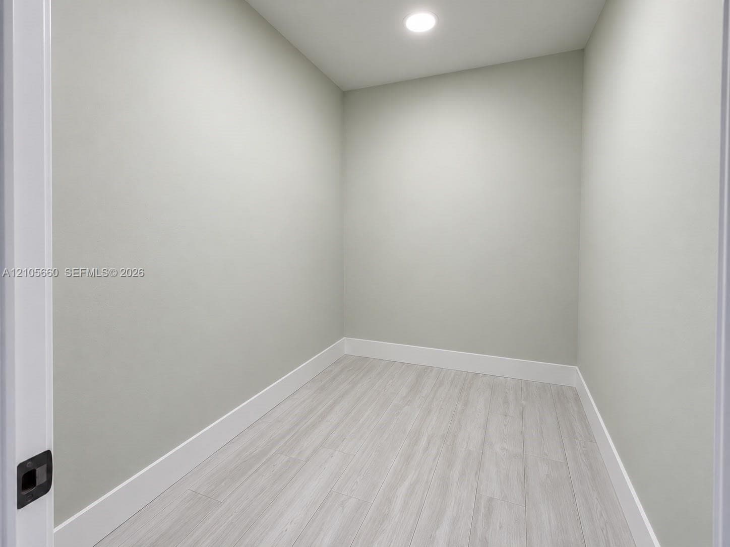 Neutral interior room featuring wood-finish flooring, light gray wall paint, and integrated recessed ceiling lighting