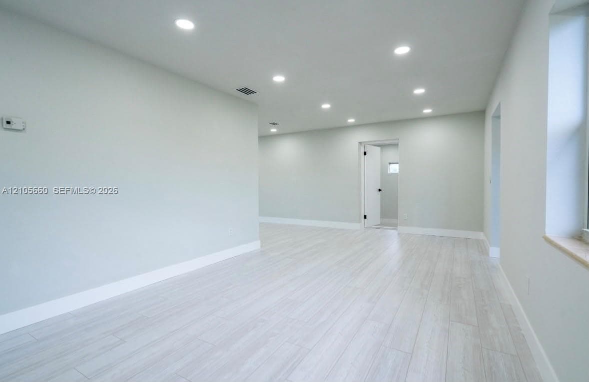 Neutral interior space featuring wood-finish flooring, recessed lighting, and crisp wall finishes
