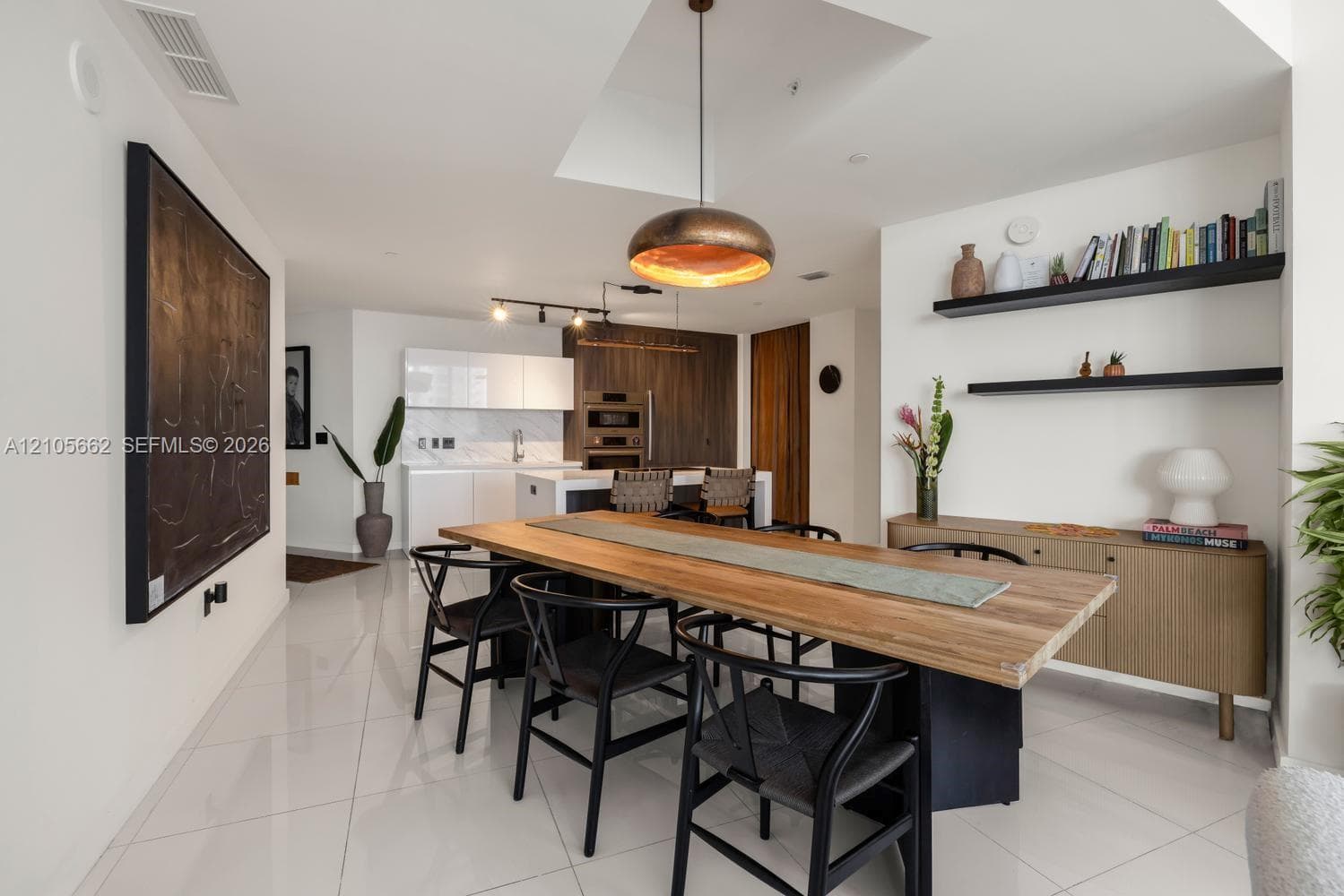 Kitchen featuring flat-panel cabinetry, built-in double ovens, stone-finish countertops, tile flooring, and metallic pendant lighting