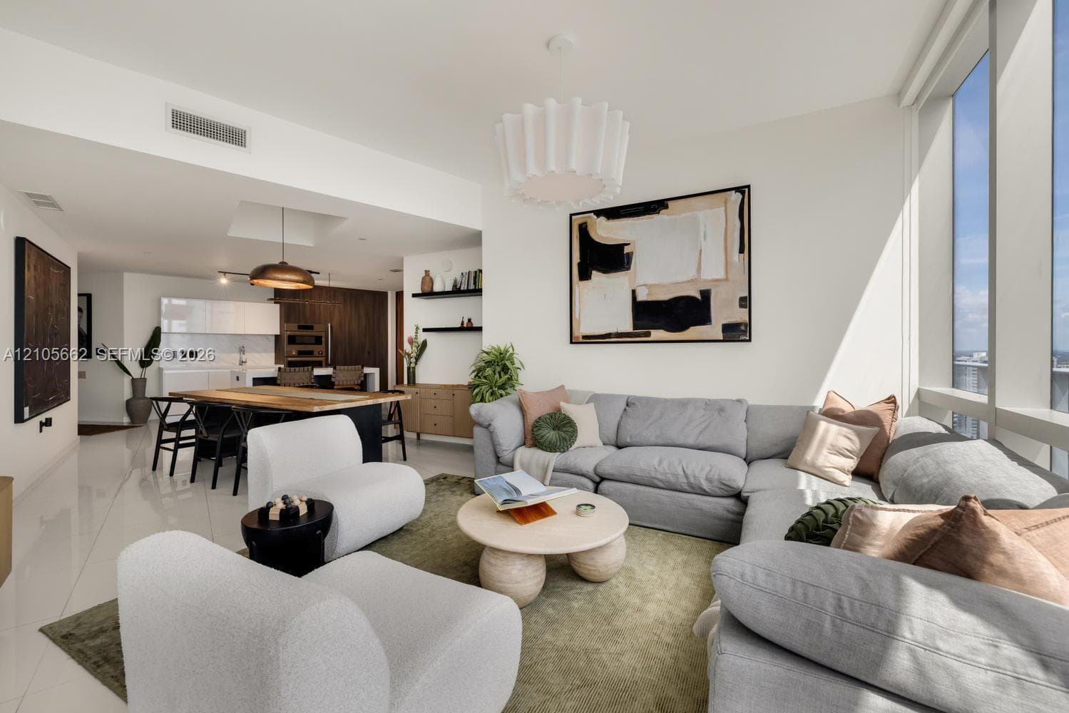 Open-concept floor plan featuring polished tile flooring, floor-to-ceiling windows, built-in shelving, and a tiered pendant light fixture