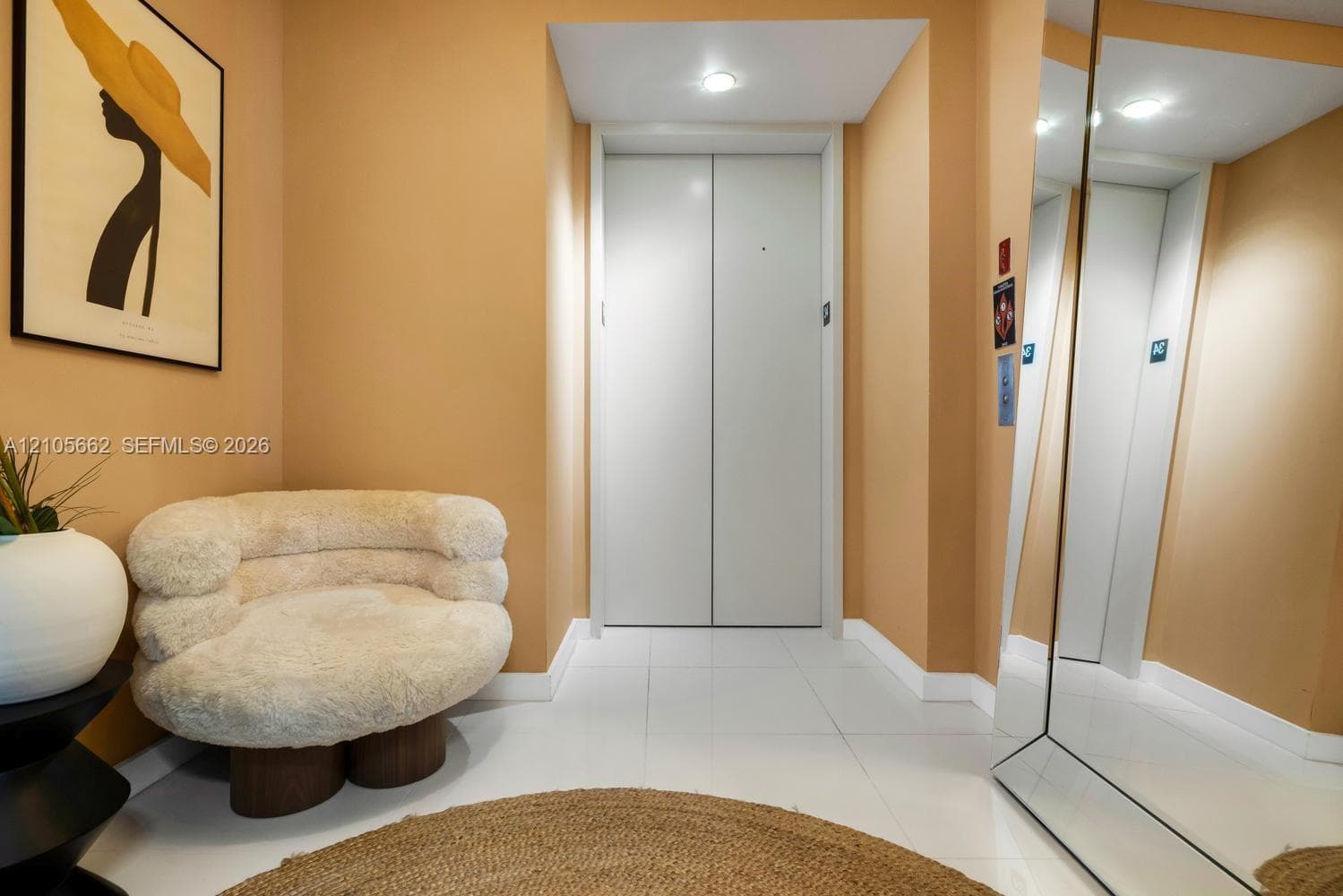Private elevator access featuring smooth-finish metal doors, recessed ceiling lighting, and reflective wall-mounted mirror paneling
