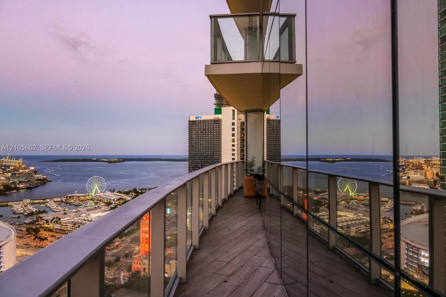 Wraparound balcony featuring glass panel railings, wood-finish flooring, and floor-to-ceiling exterior glazing
