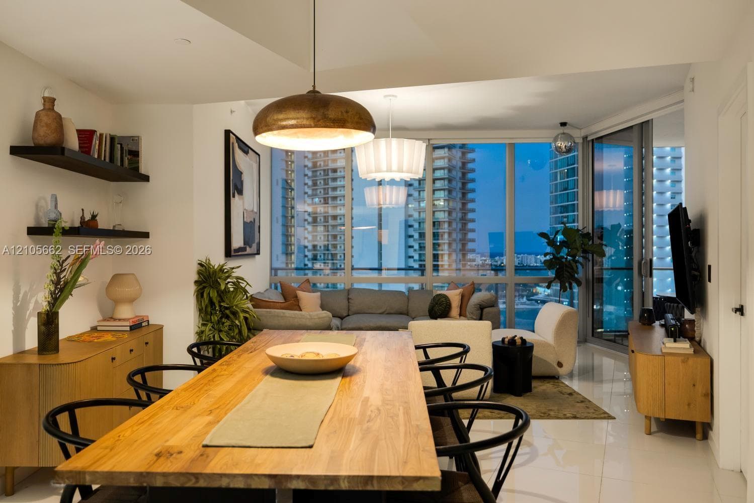 Open-concept interior featuring floor-to-ceiling glass windows, high-gloss tile flooring, built-in wall shelving, and metallic pendant lighting