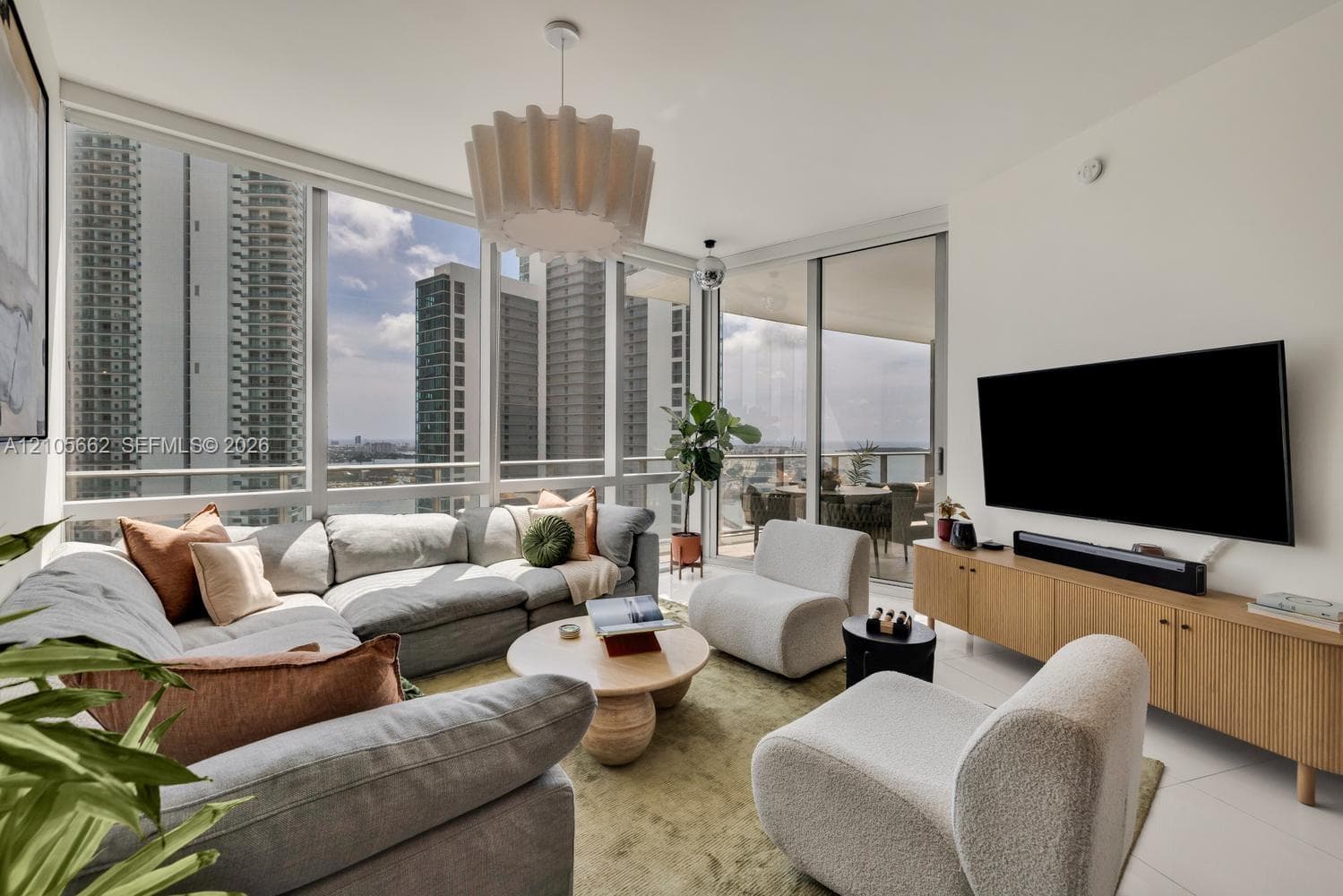 Floor-to-ceiling windows, wrap-around balcony access, neutral tiled flooring, and modern pendant lighting