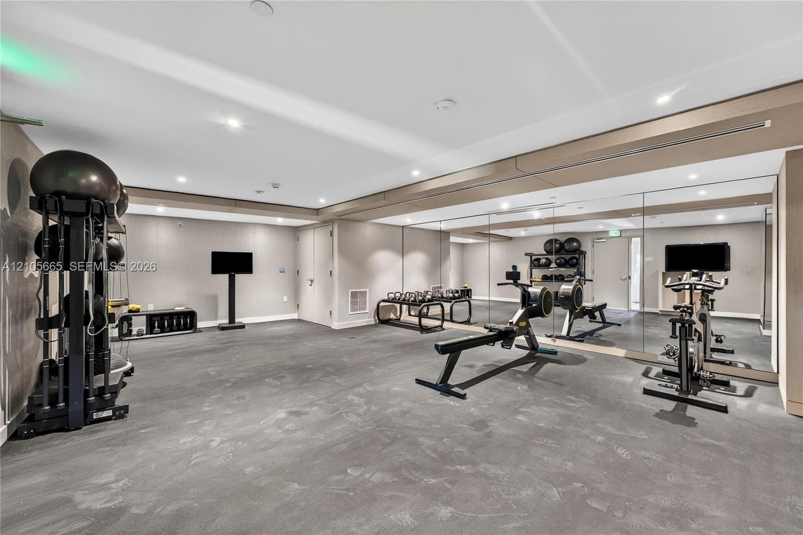 Fitness area featuring recessed ceiling lighting, wall-to-wall mirrors, and durable flooring