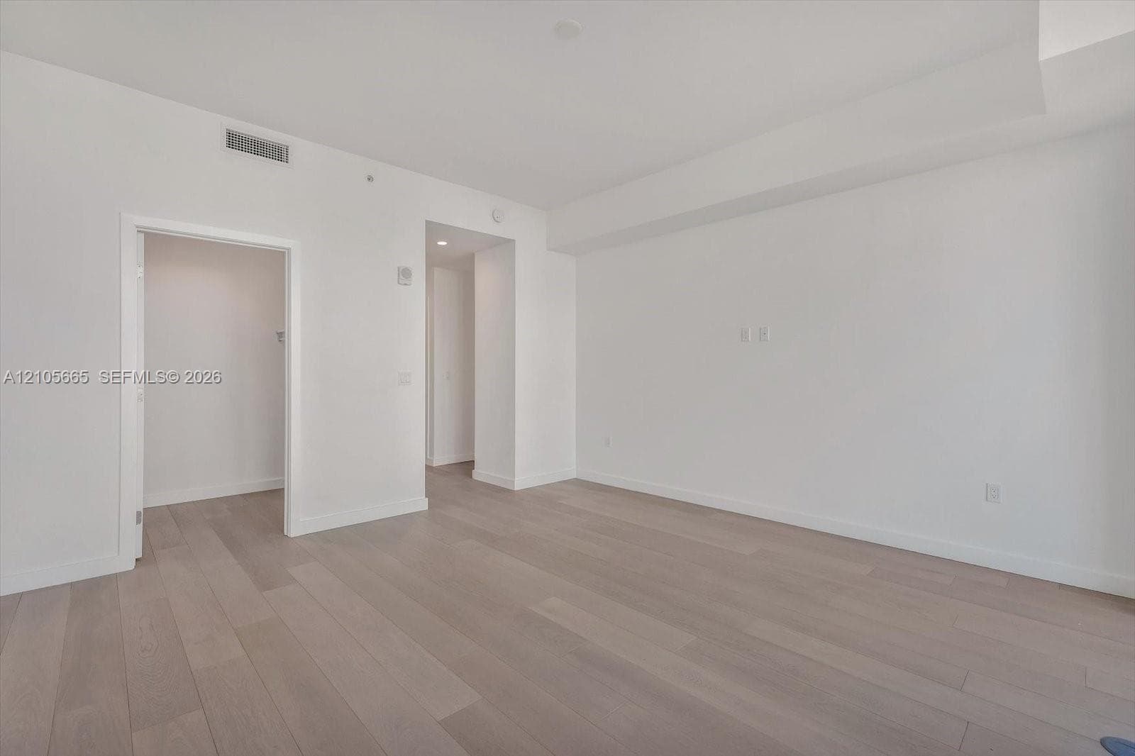 Neutral-toned wood-finish flooring, crisp white walls, and recessed ceiling lighting