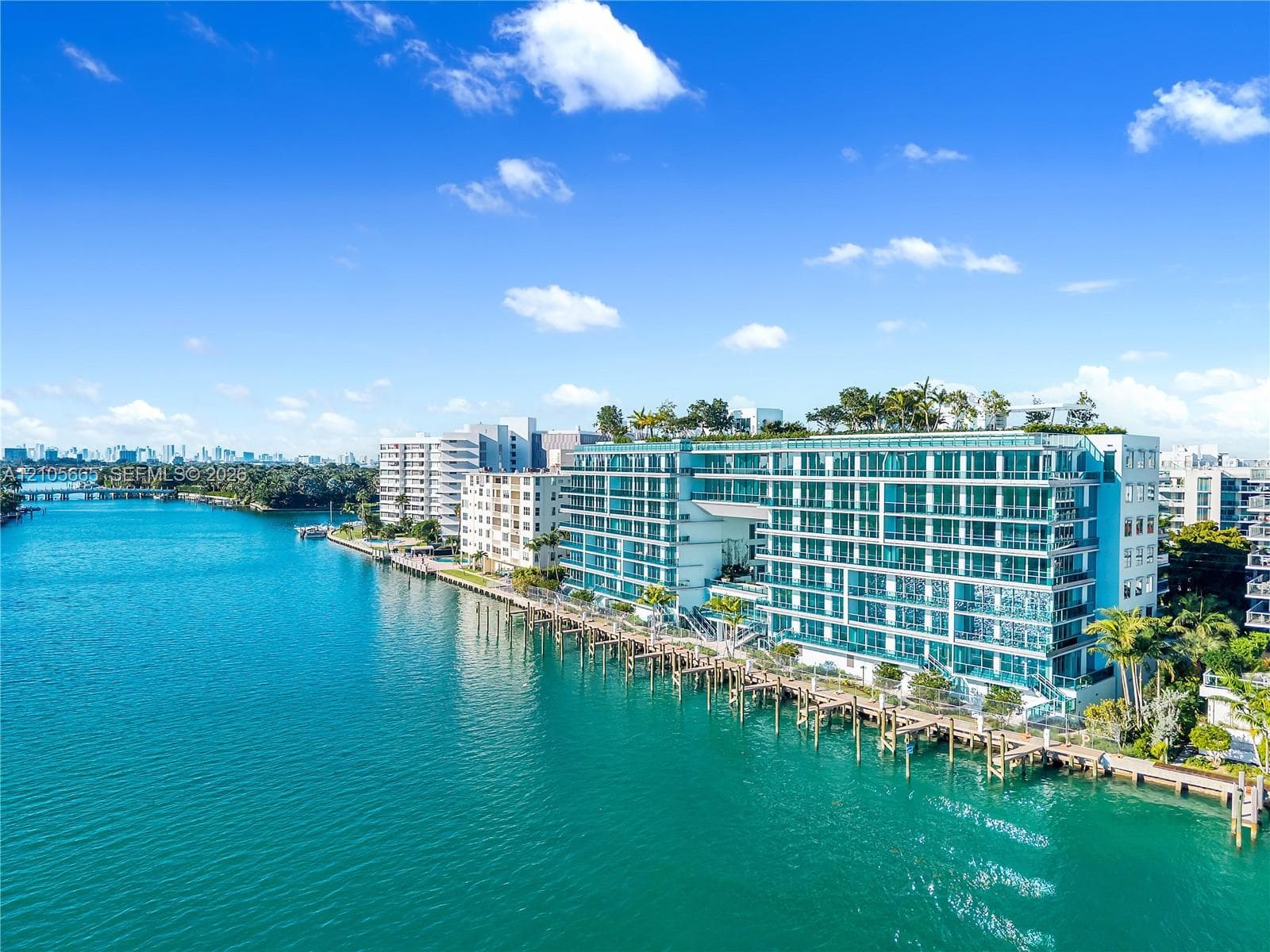 Waterfront mid-rise structure featuring floor-to-ceiling glass paneling, balcony access, rooftop landscaping, and private dockage
