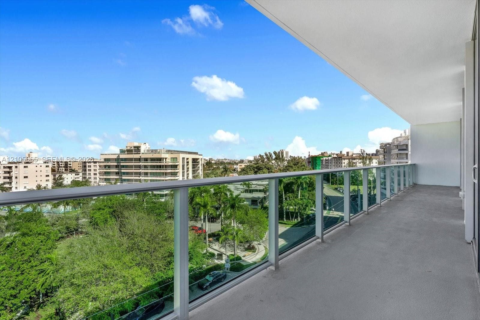 Covered balcony featuring concrete flooring and a glass-paneled railing