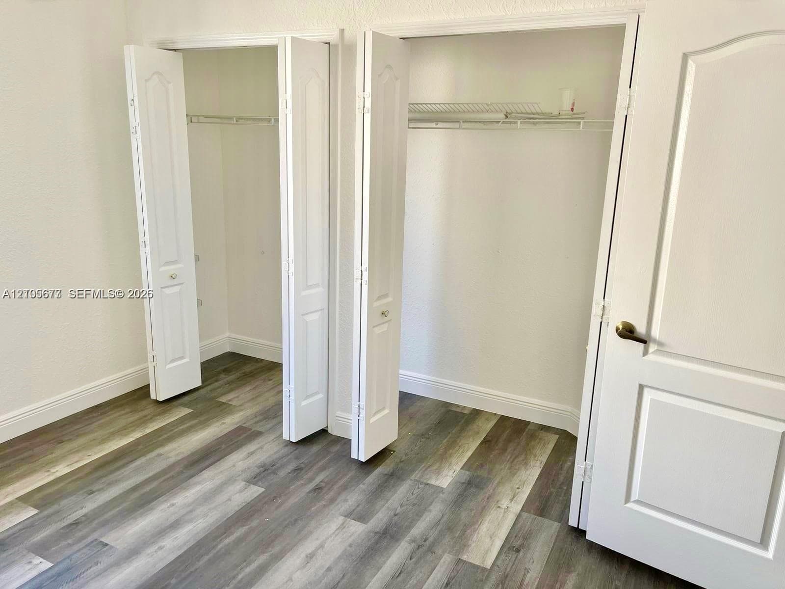 Dual reach-in closets featuring bi-fold doors, white interior finishes, wire shelving, and wood-finish flooring