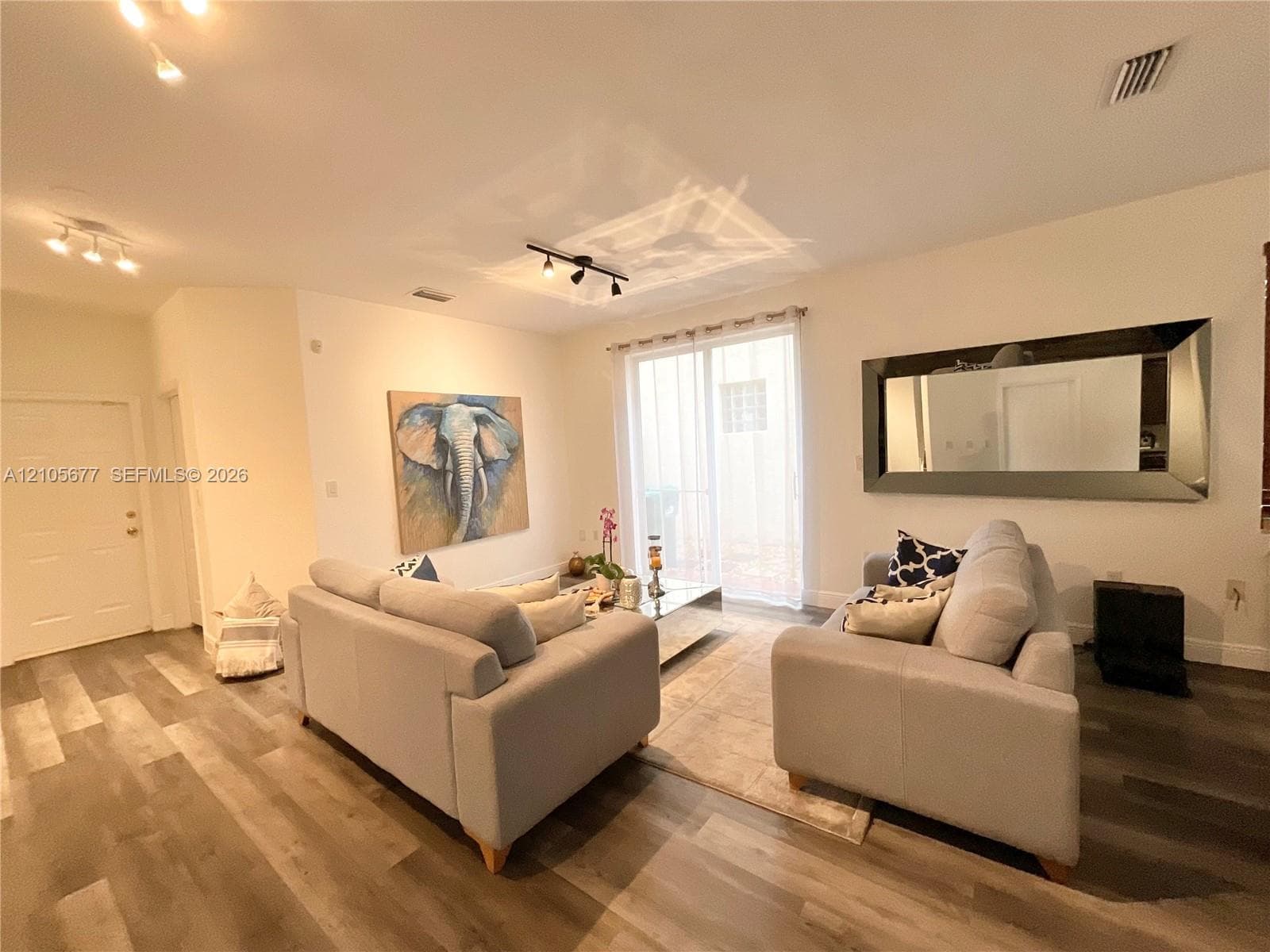 Wood-finish flooring, recessed multi-directional track lighting, and sliding glass door with access to exterior space
