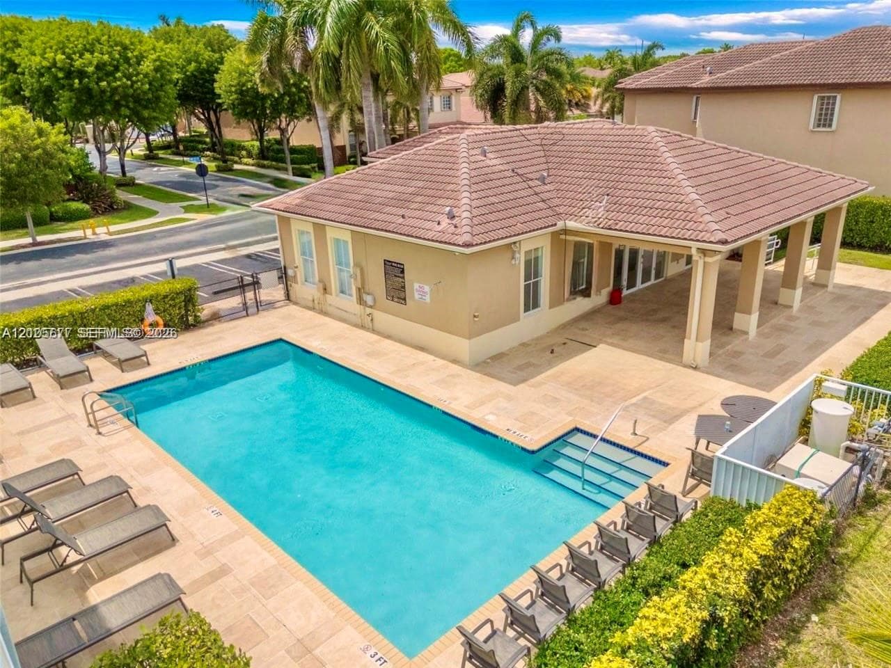 Swimming pool with integrated steps, expansive paver-stone decking, and covered outdoor patio area