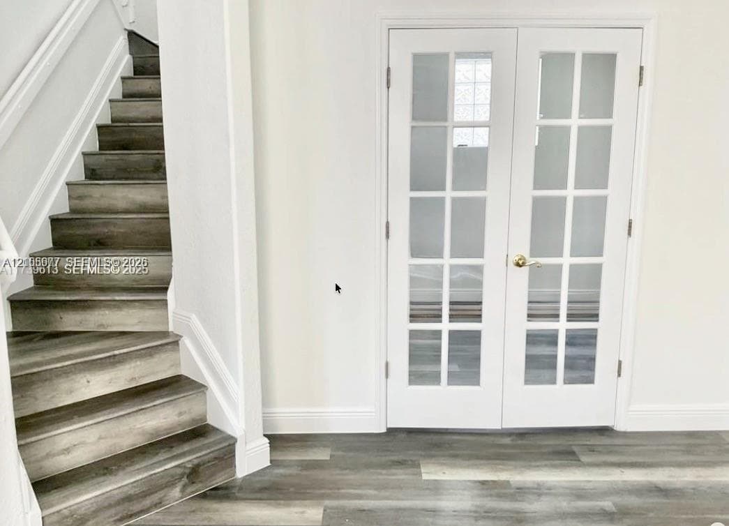 Staircase featuring wood-finish treads and white French doors with glass pane inserts