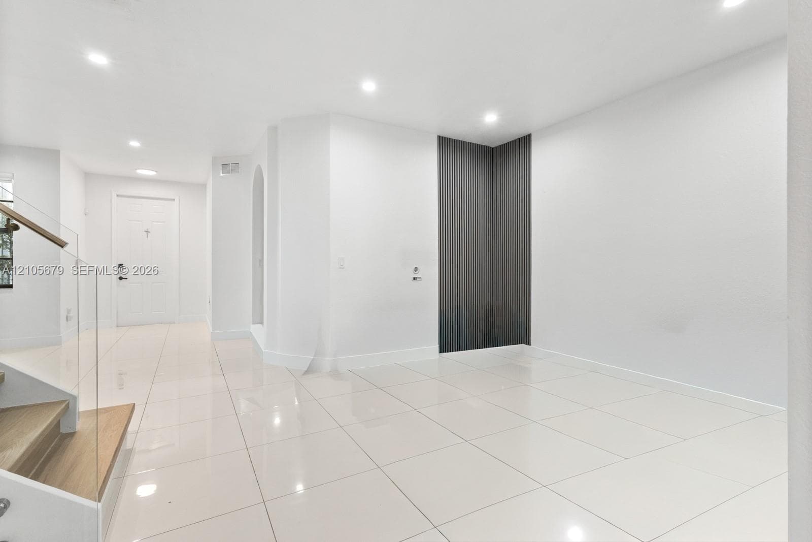 Interior space featuring large-format tile flooring, recessed lighting, and a modern glass-panel staircase railing