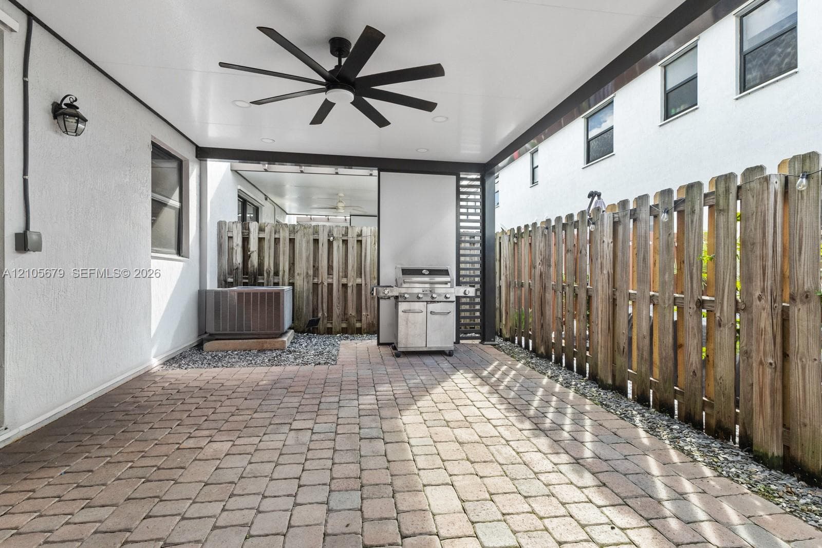 Covered patio featuring paver flooring, multi-blade ceiling fan, recessed lighting, and wood privacy fencing