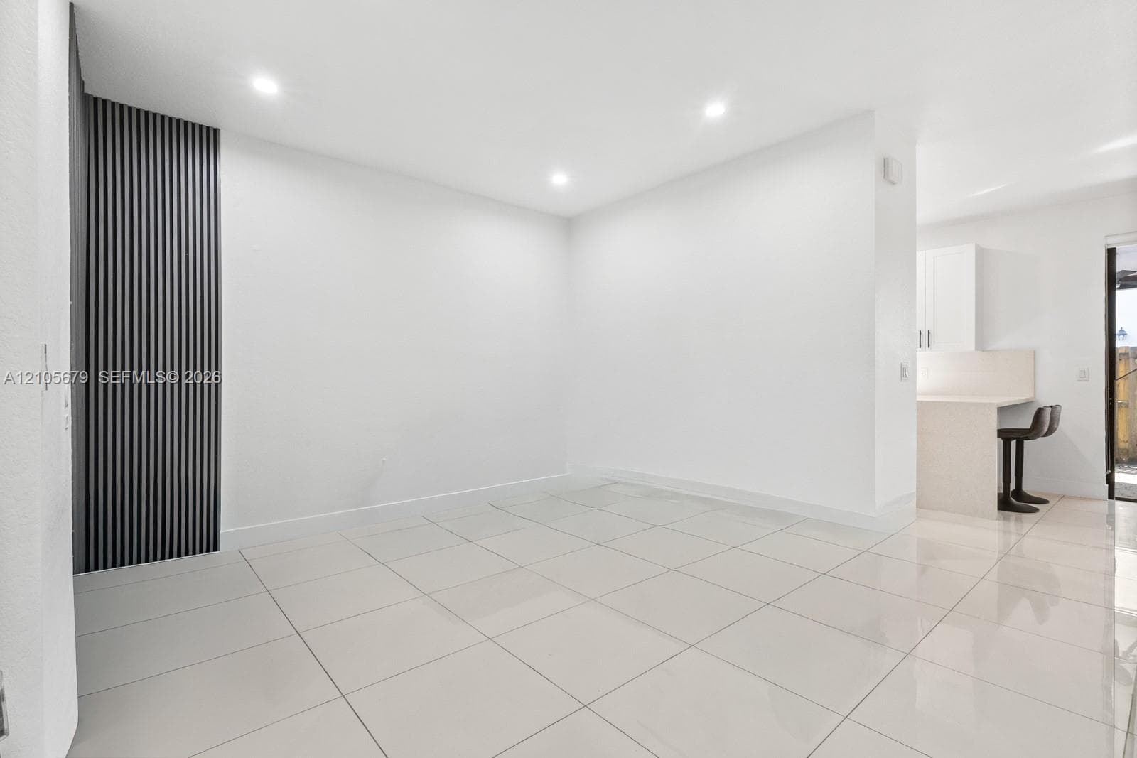 Large-format tile flooring, vertical slat accent wall, and recessed lighting