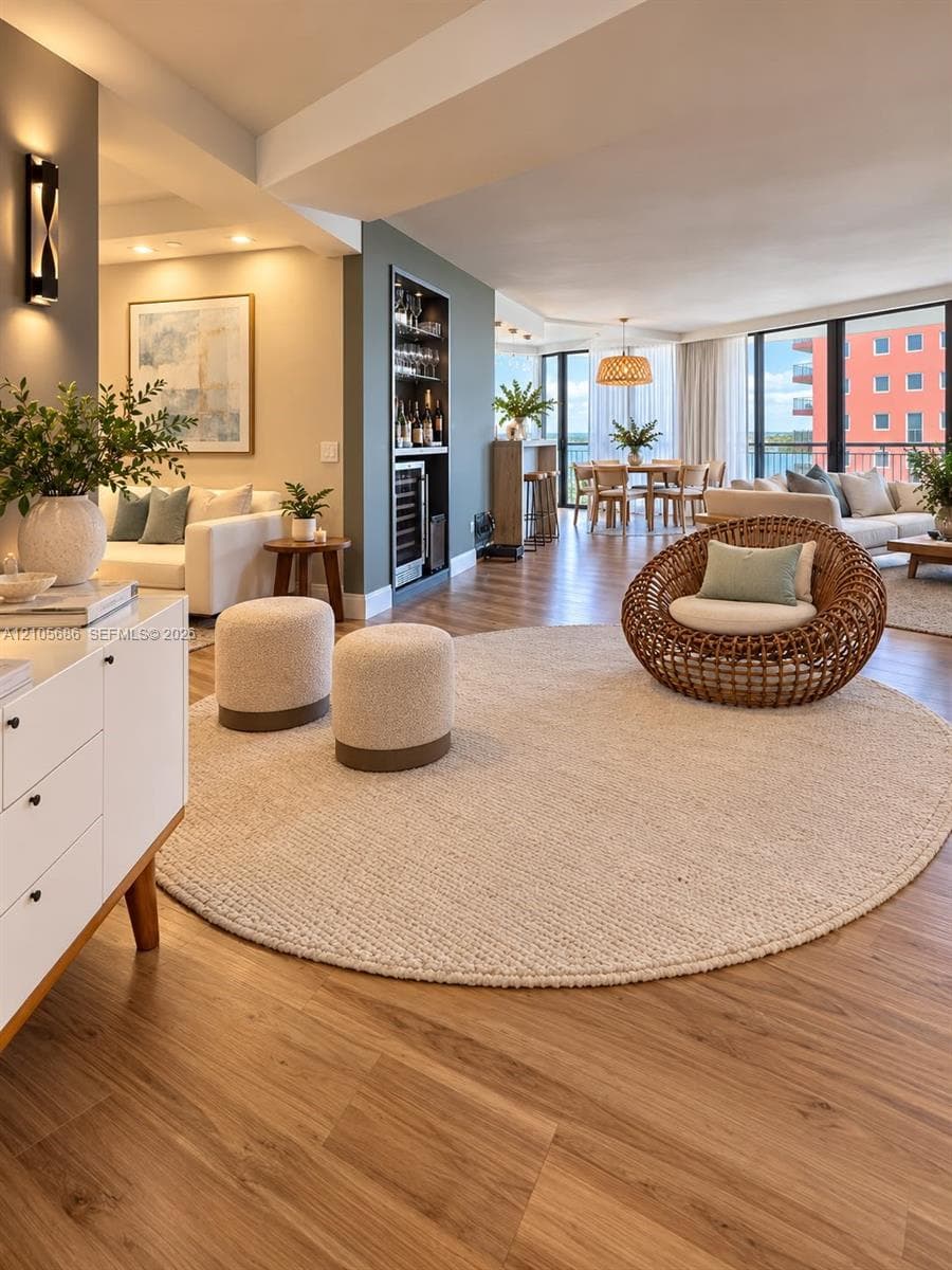 Wood-finish flooring throughout featuring a built-in recessed wet bar with integrated beverage refrigeration, expansive floor-to-ceiling windows, and wall-mounted sconce lighting