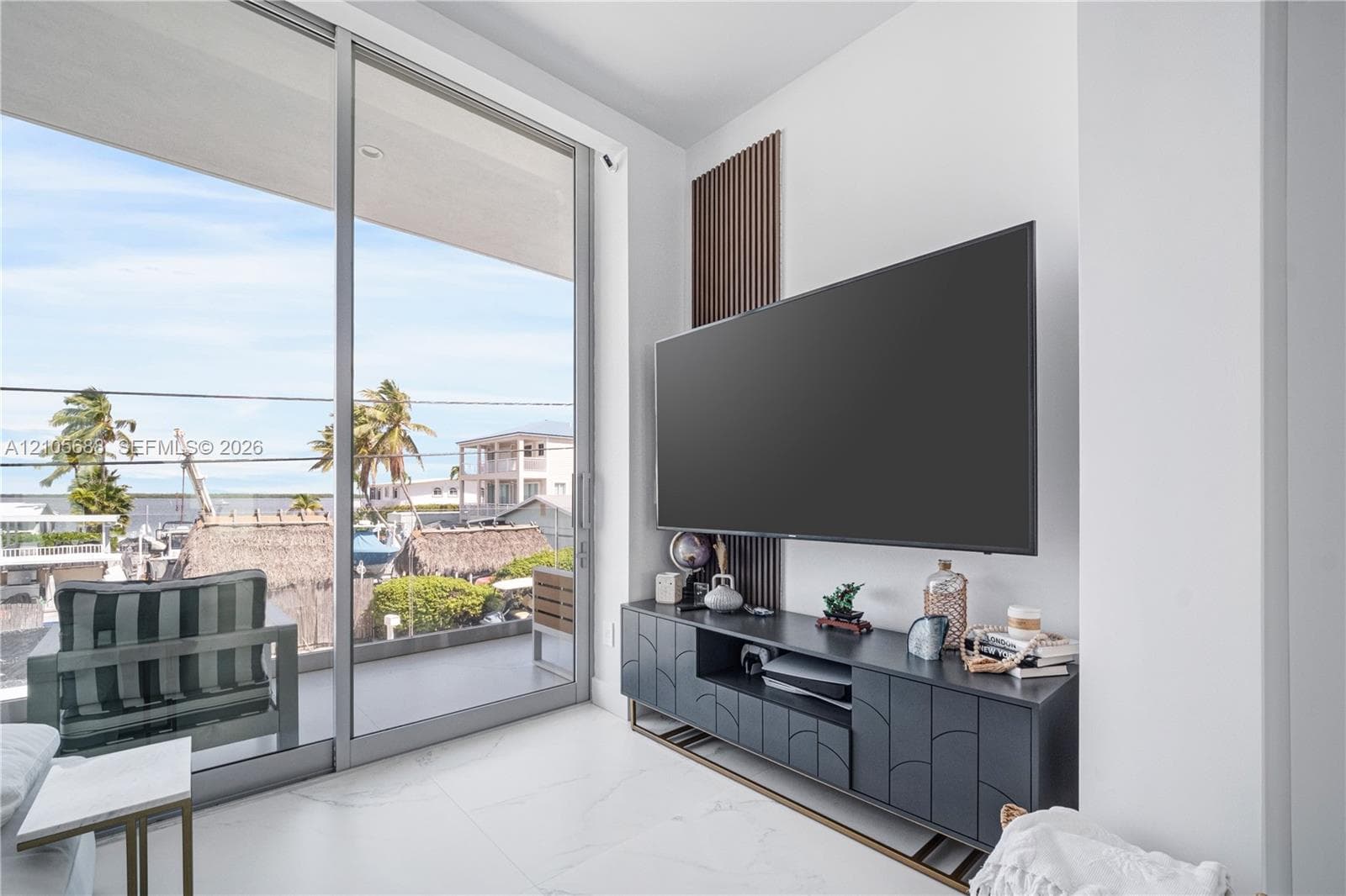 Floor-to-ceiling sliding glass doors, white stone-finish tile flooring, and a decorative vertical slat wood wall accent