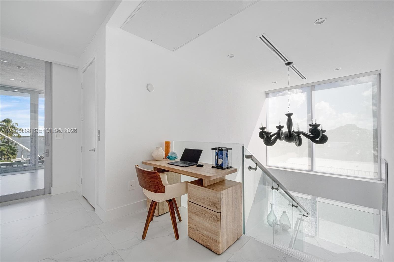 Large-format tile flooring, glass panel stair railing with stainless steel hardware, and modern black sculptural chandelier