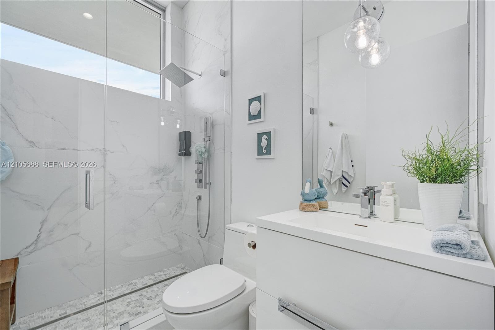 Bathroom featuring a glass-enclosed walk-in shower with stone-patterned tile, a wall-mounted rainfall showerhead, a modern white vanity, and a transom window