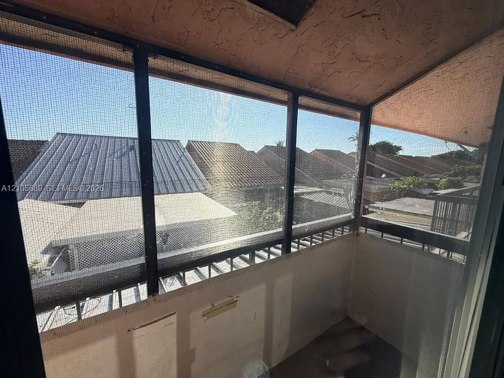 Enclosed balcony featuring black metal framing, screen panels, and a textured ceiling