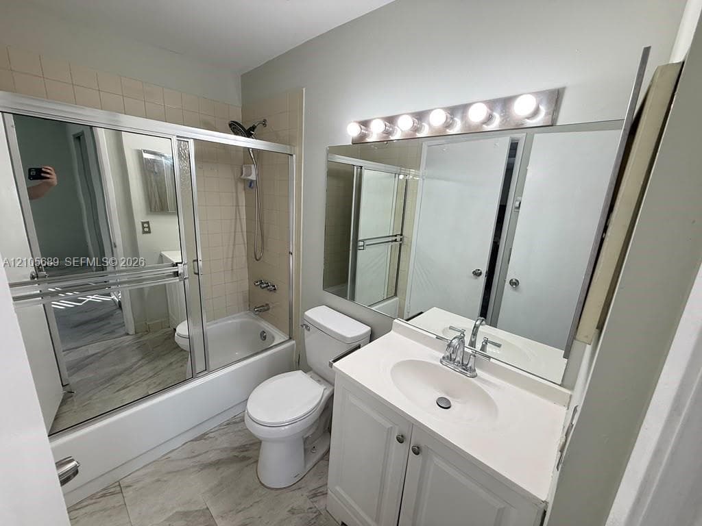 Bathroom featuring a vanity with integrated sink, large wall-to-wall mirror, six-light vanity fixture, and a tub-shower combination with sliding glass doors